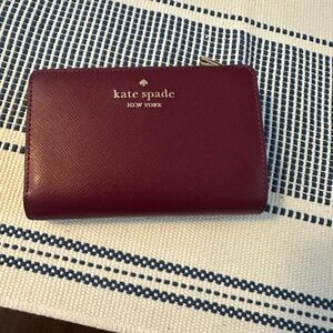 NWOT Kate Spade Medium Schuyler burgundy zip-around wallet with gold logo